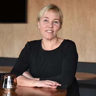 Kvine med lyst hår og mørk genser